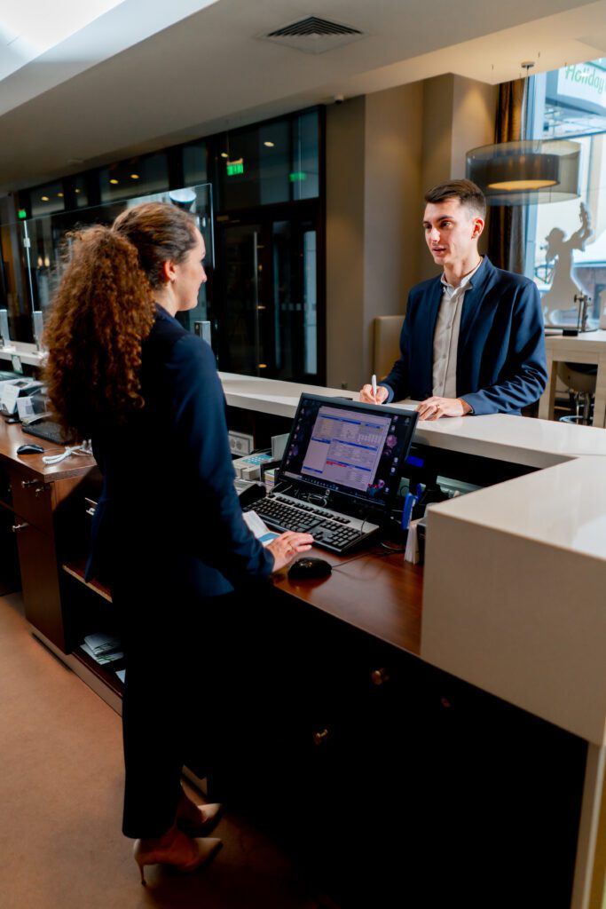 The receptionist at the counter meets the guest with luggage in hotel business travel hospitality